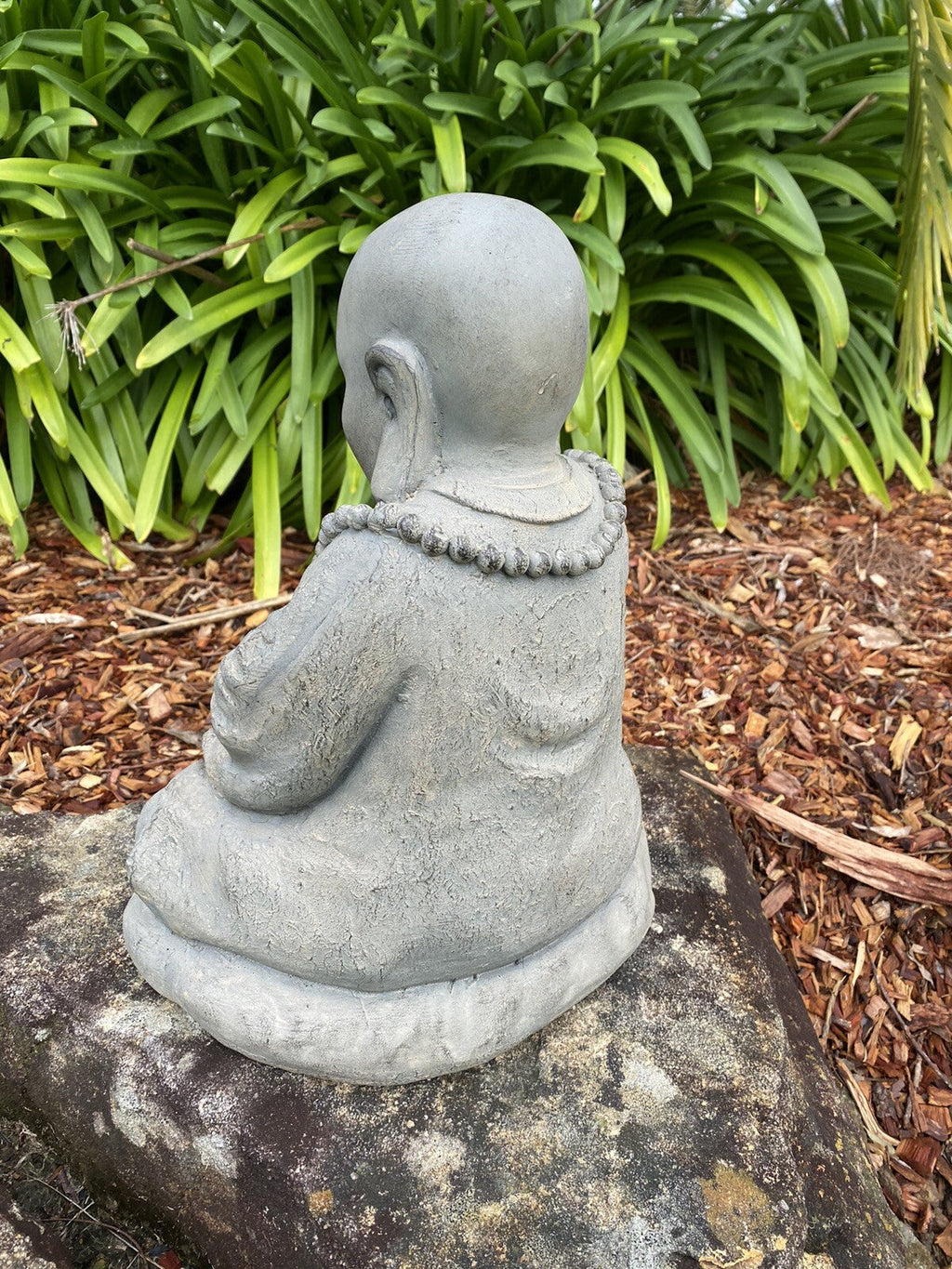 22nice4me Garden Statues Buddha figurine in GRC concrete with an antique finish, viewed from the back in a garden.