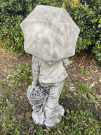 22nice4me Garden Statues concrete boy statue holding an umbrella and flower basket, back view in a garden setting.