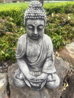 22nice4me Garden Statues concrete Buddha in a seated meditation pose with a weathered grey finish in a garden setting