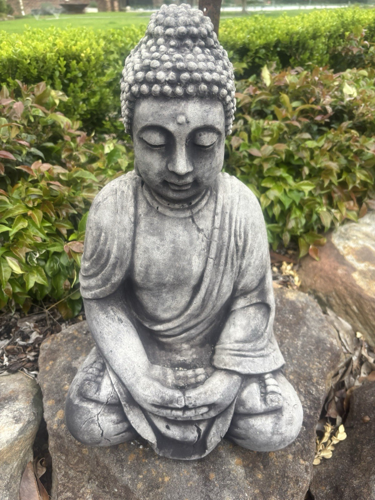 22nice4me Garden Statues concrete Buddha in a seated meditation pose with a weathered grey finish in a garden setting