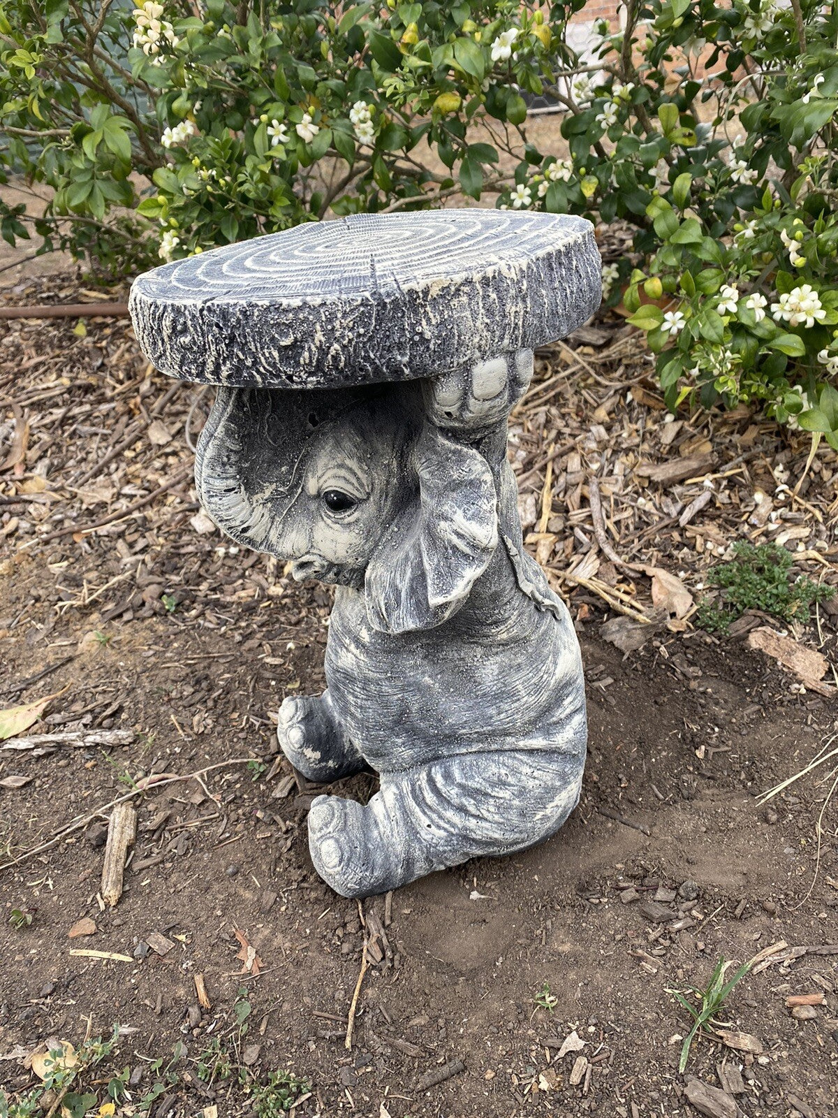 22nice4me Garden Statues grey concrete elephant plant stand with a faux wood grain top in a garden setting