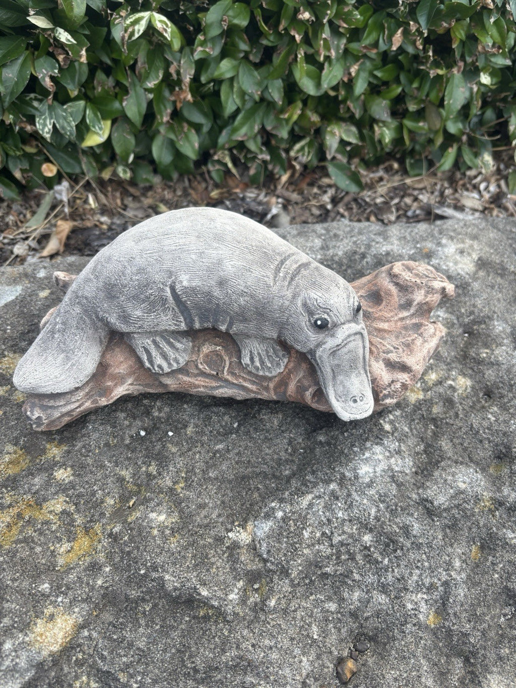 22nice4me Garden Statues concrete platypus resting on a rustic log, featuring detailed fur and bill texture.
