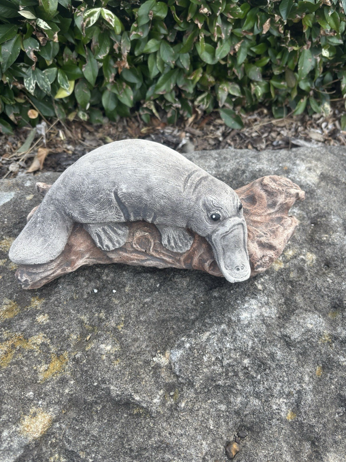 22nice4me Garden Statues concrete platypus resting on a rustic log, featuring detailed fur and bill texture.