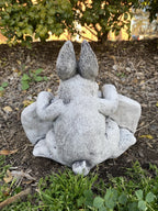 Back view of a 22nice4me Garden Statues concrete rabbit statue with textured fur detail sitting in a garden bed