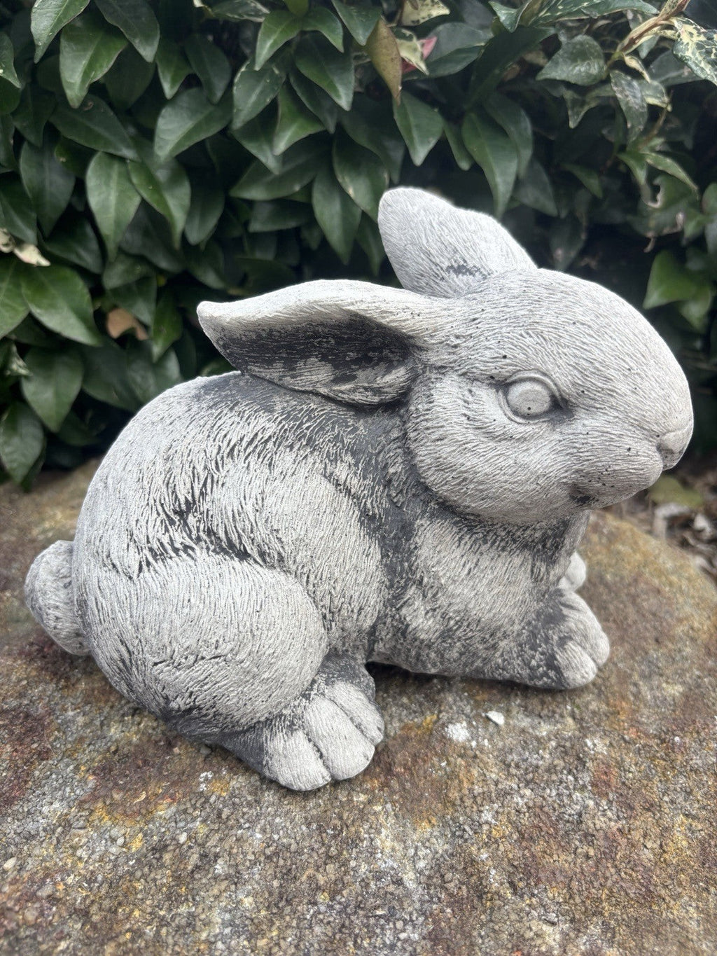 handcrafted grey concrete rabbit sculpture with realistic fur texture in a garden setting