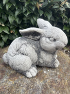 handcrafted grey concrete rabbit sculpture with realistic fur texture in a garden setting