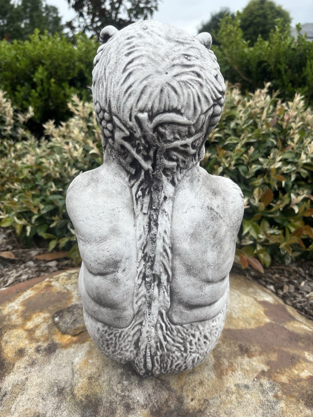 Back view of 22nice4me Garden Statues concrete Pan statue with an antique finish, set in a garden.