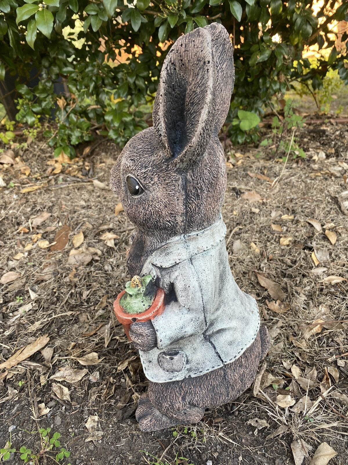 22nice4me Garden Statues Peter Rabbit concrete ornament holding a potted plant and spade in a garden setting