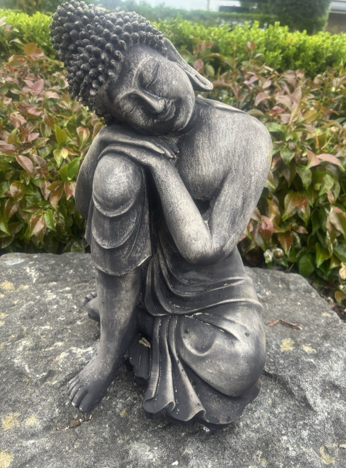 22nice4me Garden Statues dark grey concrete sleeping Buddha ornament with a weathered finish in a garden setting