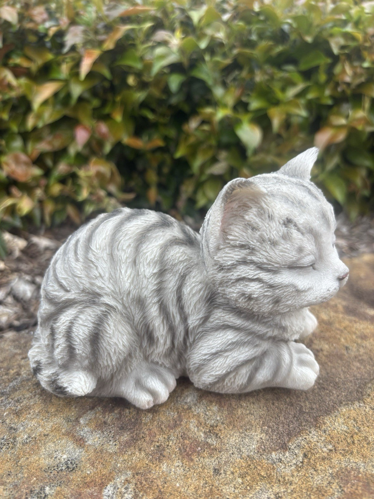 22nice4me Garden Statues sleeping grey tabby cat ornament with textured fur, resting on a stone surface outdoors.