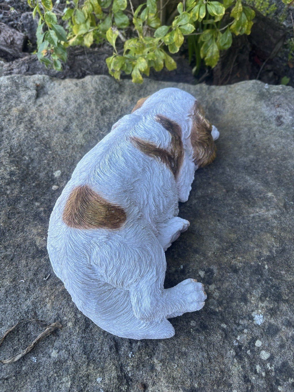 resin Cavalier King Charles Spaniel ornament in a relaxed laying pose on a stone surface